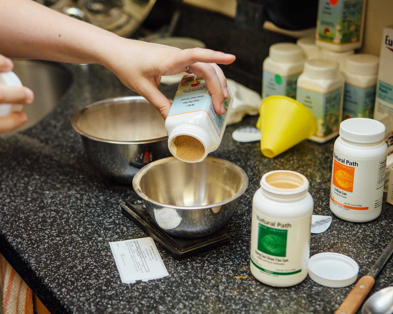Herbal Powder Being Poured into a Metal Bowl Seated on a Countertop