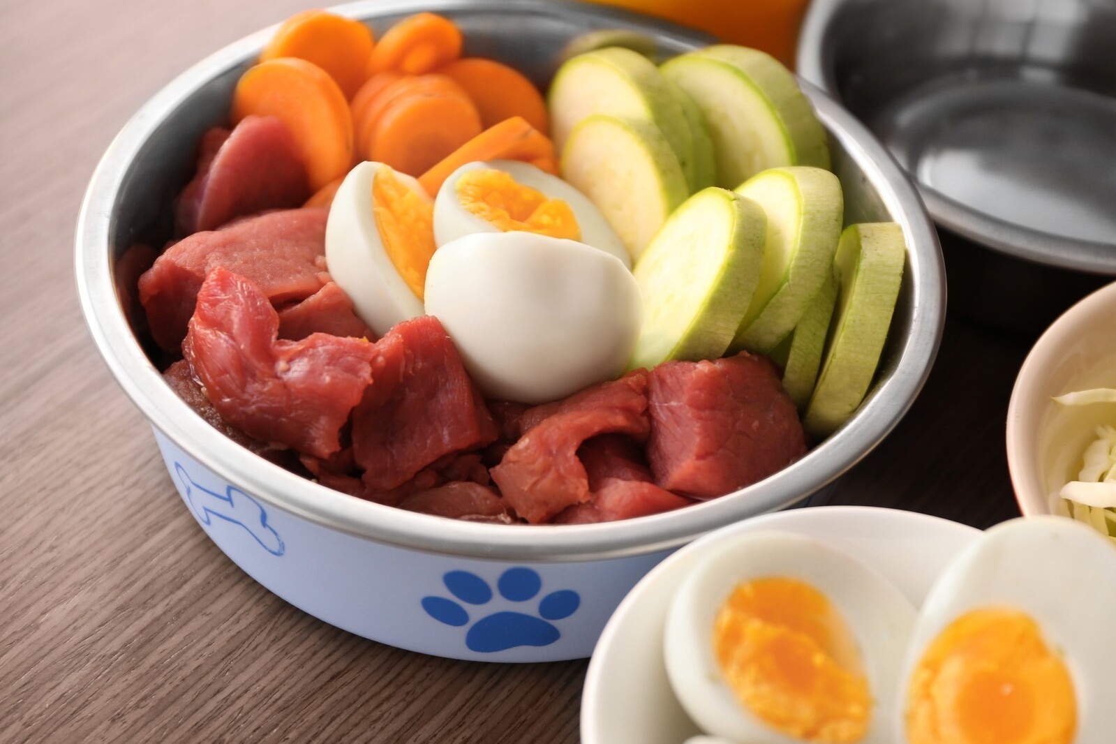 Vegetables, Eggs and Raw Meat in a White Dog Bowl with Paw Prints